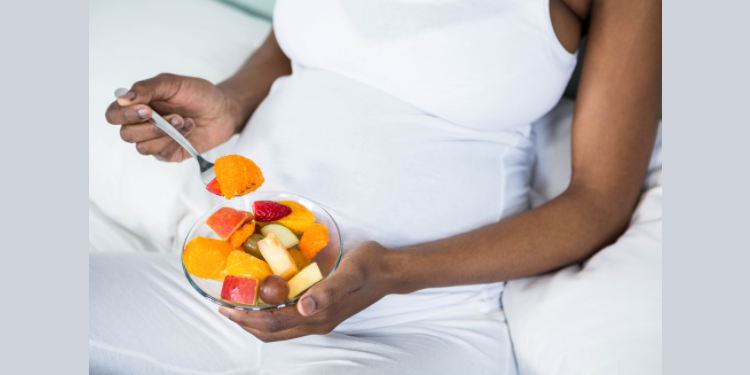 heavily pregnant woman snacking on fruits