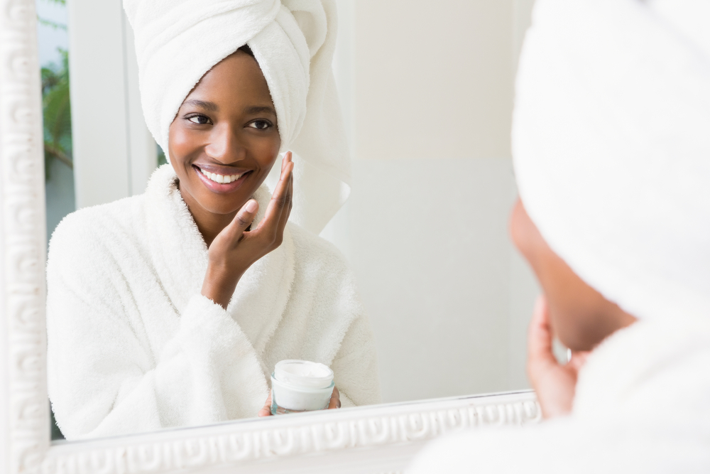 Woman standing at the mirror to pamper her skin