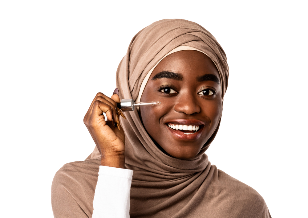 Happy Muslim woman holding a skin care serum