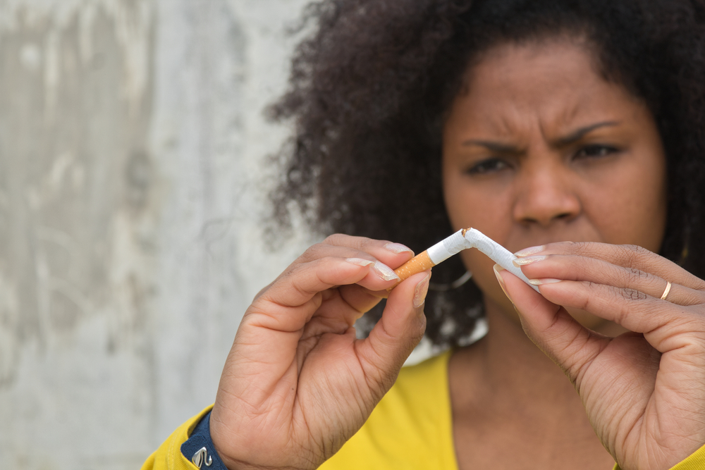 Black woman breaking a stick of cigarette
