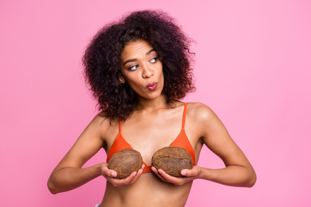 Woman holding two coconuts over her breasts
